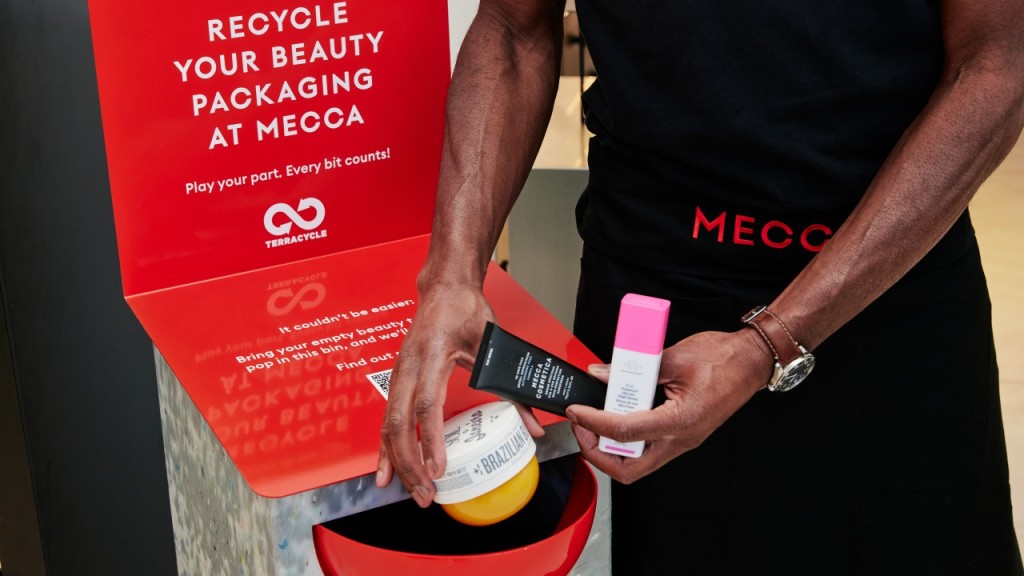 Person dropping empty beauty products into a recycling collection bin at MECCA.